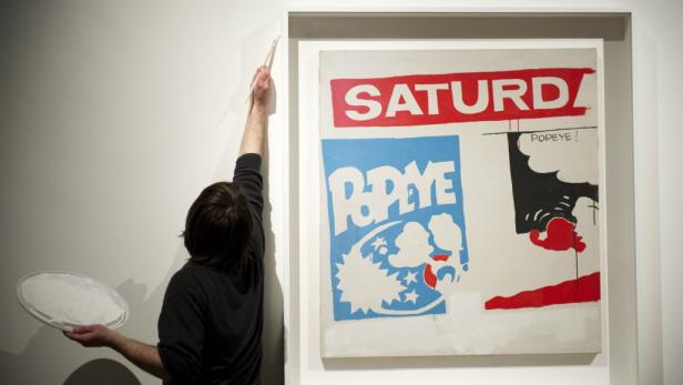 Ein Mann restauriert ein Kunstwerk mit dem Titel „Saturday Popeye“ in einer Galerie.