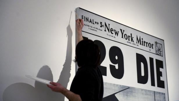 Eine Person restauriert ein großes Faksimile der Titelseite des „New York Mirror“ vom 4. Juni 1962.