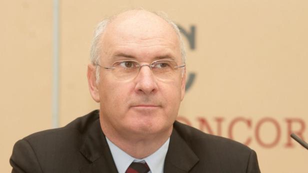 Ein Mann mit Brille und dunklem Anzug blickt aufmerksam zur Seite.