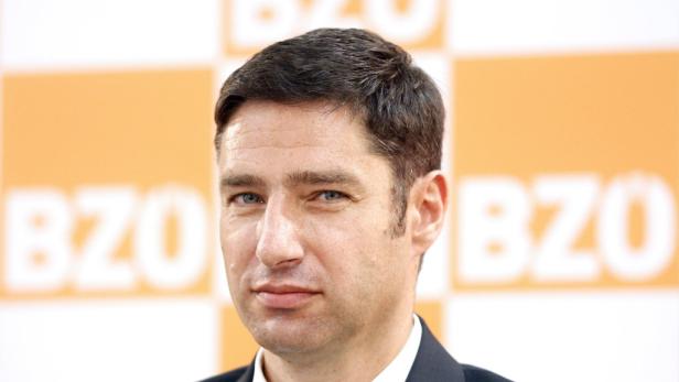 Nahaufnahme eines Mannes vor einem orangefarbenen Hintergrund mit der Aufschrift „BZÖ“.