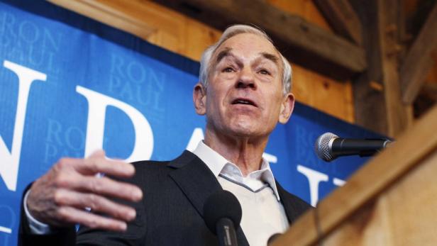 Ron Paul spricht vor einem blauen Banner mit seinem Namen.
