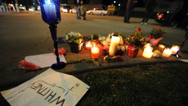 Eine Gedenkstätte mit Kerzen, Blumen und einem handgeschriebenen Schild für Whitney.