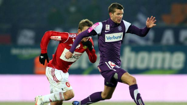 Zwei Fußballspieler kämpfen um den Ball auf dem Spielfeld.