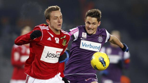 Zwei Fußballspieler kämpfen um den Ball während eines Spiels.