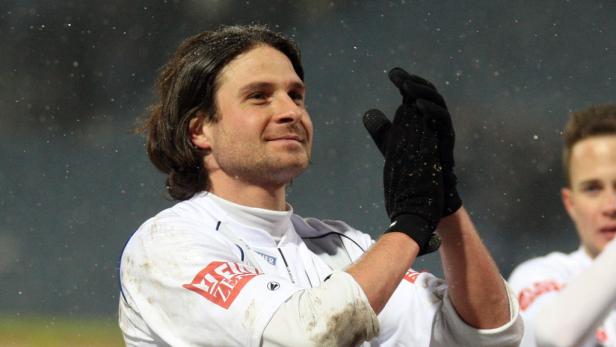 Ein Fußballspieler klatscht mit Handschuhen in die Hände.