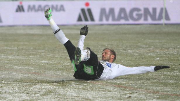 Ein Fußballspieler liegt auf dem schneebedeckten Feld.