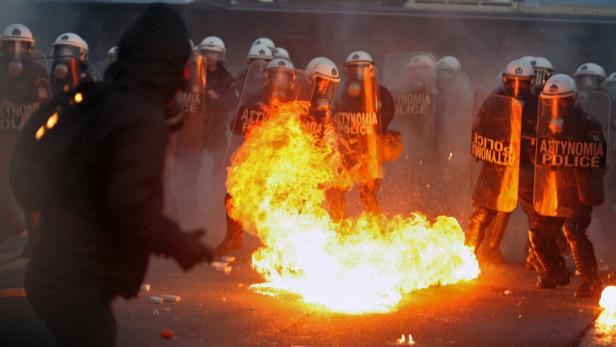 Bei einer Demonstration stehen sich Polizisten in Schutzkleidung und ein Feuer gegenüber.