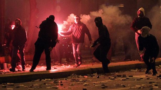 Eine Gruppe von Demonstranten zündet Rauchbomben und wirft mit Steinen.
