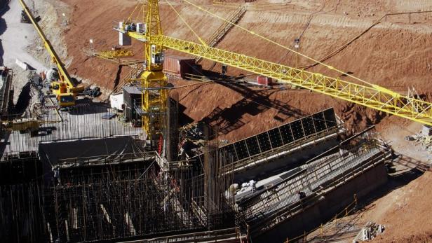 Zwei gelbe Baukräne auf einer Baustelle mit roter Erde im Hintergrund.