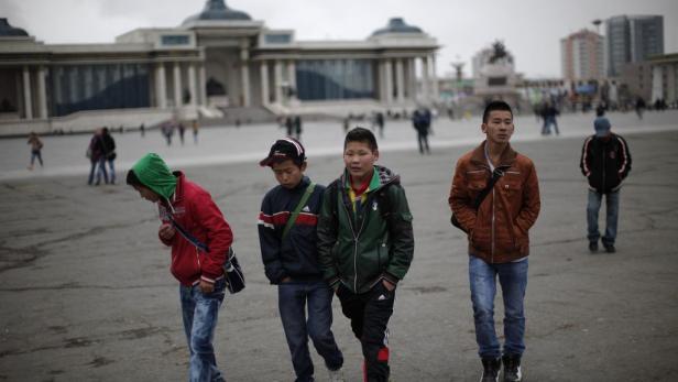 Eine Gruppe junger Männer geht über einen Platz in Ulaanbaatar, Mongolei.