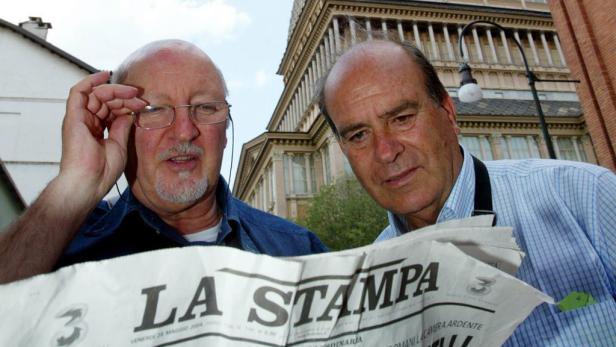 Zwei Männer lesen die Zeitung „La Stampa“ vor einem Gebäude in Turin.