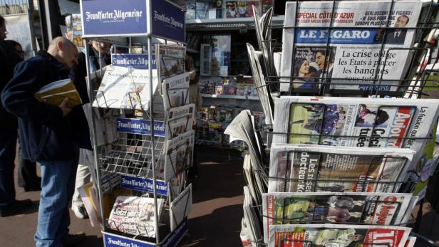 Ein Mann kauft Zeitungen an einem Kiosk, darunter die Frankfurter Allgemeine und Le Figaro.