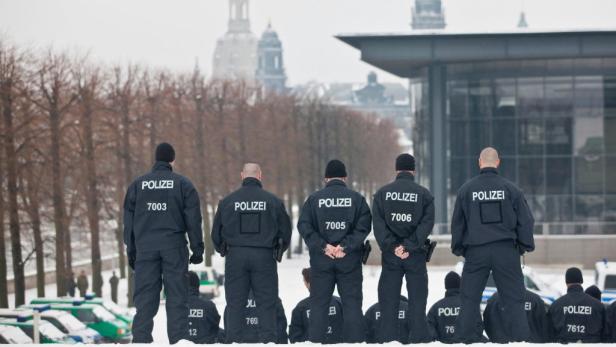 Eine Gruppe Polizisten steht im Winter vor einem Gebäude in Dresden.