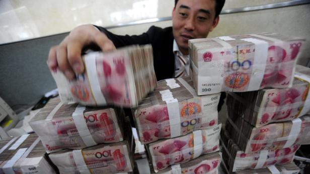 Ein Mann hantiert mit Stapeln von chinesischen 100-Yuan-Banknoten.