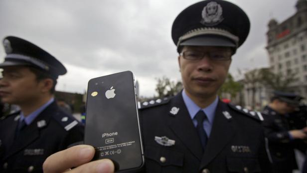 Ein chinesischer Polizist hält ein iPhone in die Kamera.