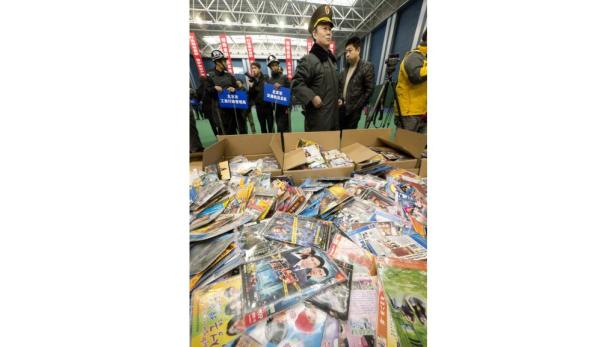 Beschlagnahmte DVDs und CDs liegen vor Beamten in Uniform auf einem Haufen.