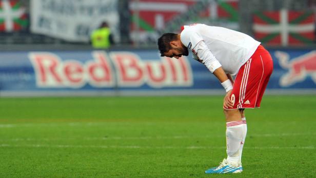 Ein Fußballspieler beugt sich mit gesenktem Kopf auf dem Spielfeld nach vorne.