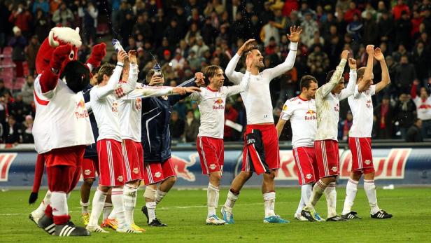 Spieler von Red Bull Salzburg feiern mit ihrem Maskottchen auf dem Rasen.
