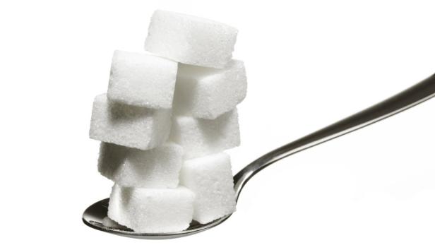 Ein Stapel Zuckerwürfel liegt auf einem Löffel.