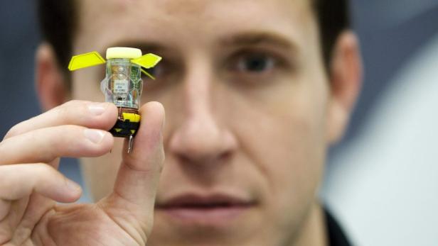 Ein Mann hält einen kleinen, elektronischen Sensor zwischen Daumen und Zeigefinger.