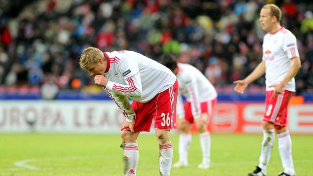 Ein Fußballspieler beugt sich erschöpft auf dem Spielfeld nach vorne.