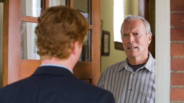 Walt Kowalski (Clint Eastwood) steht an seiner Haustür und spricht mit einem jungen Mann.