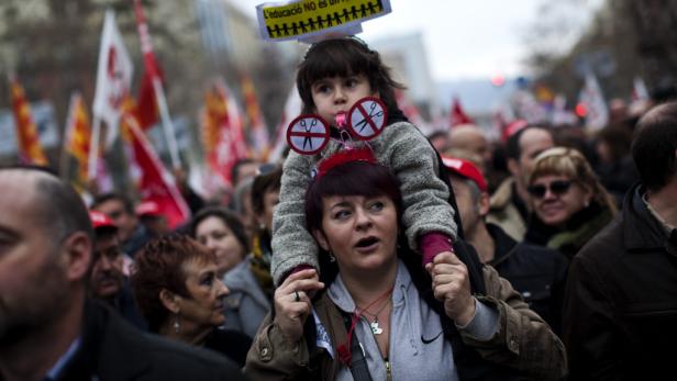 Eine Frau trägt ein Kind mit einem Schild auf den Schultern bei einer Demonstration.