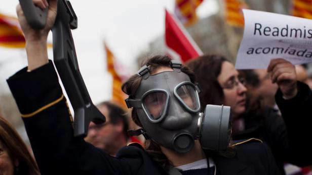 Eine Demonstrantin mit Gasmaske und Spielzeuggewehr auf einer Kundgebung.