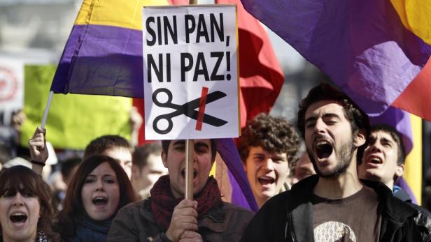 Menschen demonstrieren mit einer Fahne und einem Schild mit der Aufschrift „Sin Pan, Ni Paz!“.