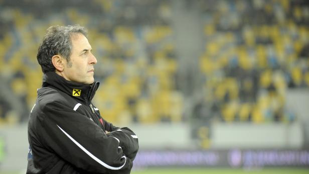 Ein Mann mit verschränkten Armen blickt auf ein Fußballfeld.