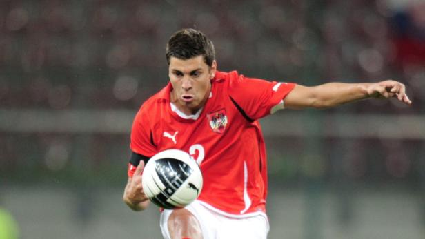 Ein österreichischer Fußballspieler in rotem Trikot mit Ball.