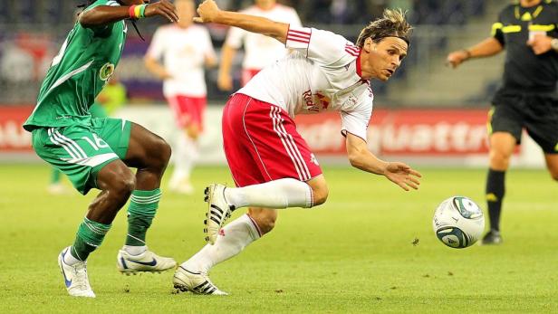Ein Fußballspieler in einem weißen und roten Trikot versucht, den Ball zu erreichen.
