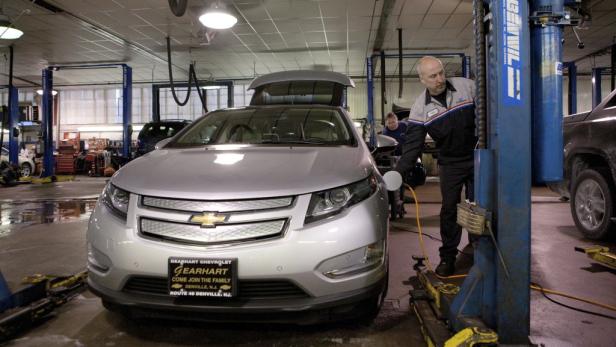 Ein Mechaniker lädt in einer Werkstatt einen silbernen Chevrolet Volt auf.