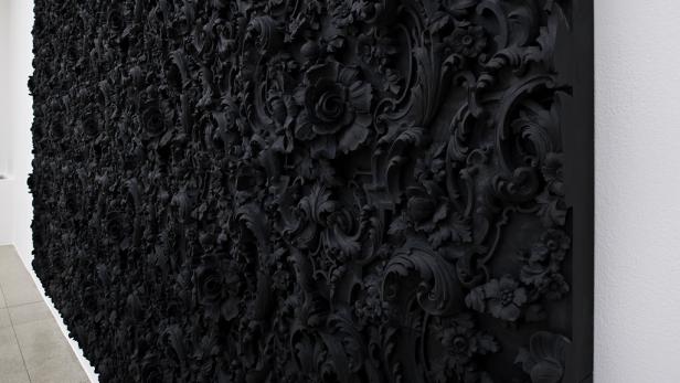 Eine Wand bedeckt mit einem schwarzen, floralen Relief.