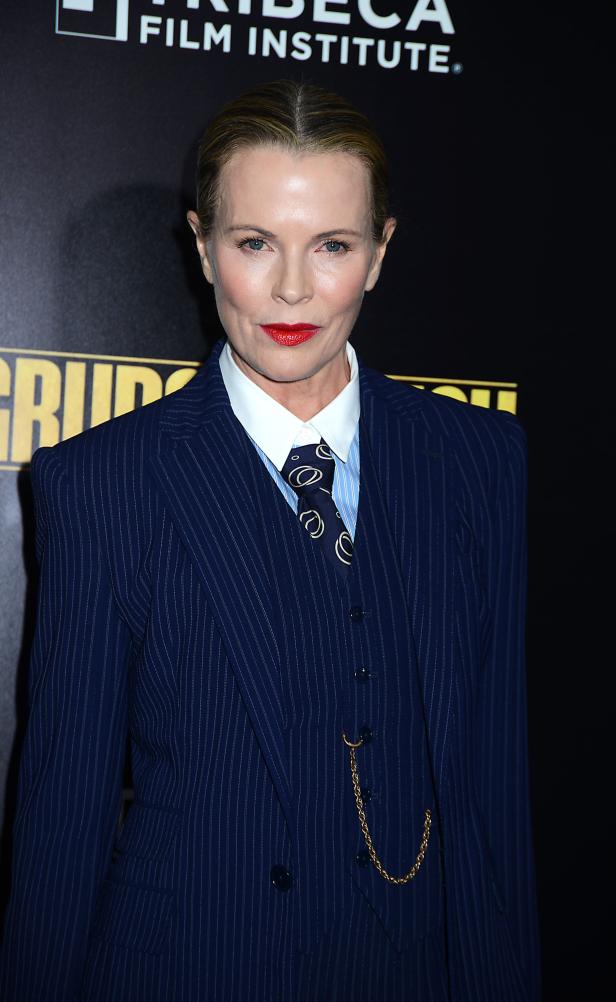 Chelsea Handler trägt einen blau gestreiften Anzug mit Krawatte und rotem Lippenstift.