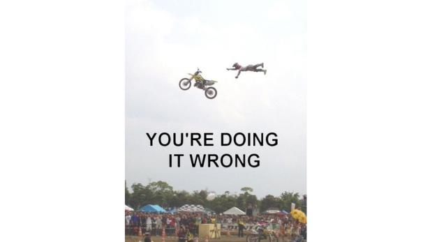 Ein Motocross-Fahrer stürzt während eines Stunts von seinem Motorrad vor einer Zuschauermenge.