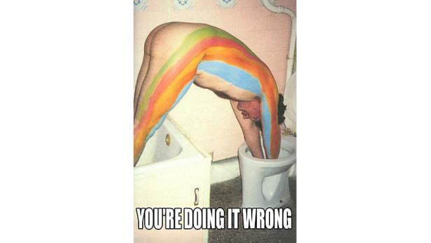 Ein Mann mit Regenbogenbemalung taucht seinen Kopf in eine Toilette.