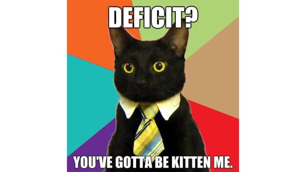 Eine schwarze Katze mit Hemd und Krawatte vor einem farbenfrohen Hintergrund mit dem Text „Defizit? Du willst mich wohl verkatzen!“.