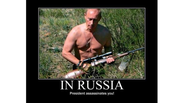 Wladimir Putin hält ein Gewehr in einer ländlichen Umgebung.