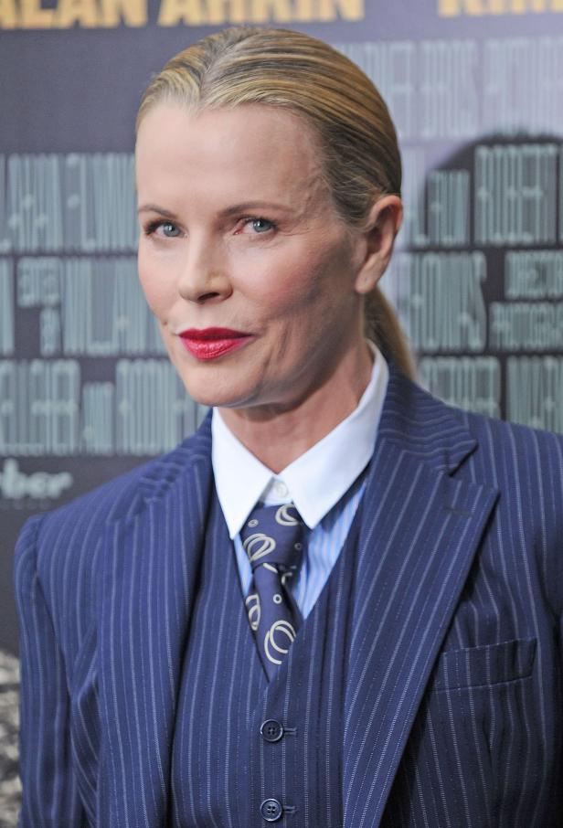 Kim Basinger in einem blau gestreiften Hosenanzug.