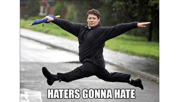 Ein Mann in schwarzer Kleidung springt mit einem Regenschirm in der Hand in der Luft.