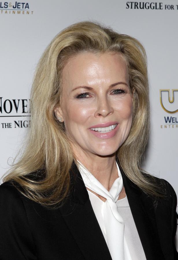 Kim Basinger lächelt in einem schwarzen Blazer und einer weißen Bluse.