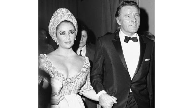 Elizabeth Taylor und Richard Burton Hand in Hand bei einer Veranstaltung.