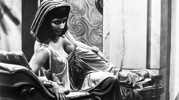 Elizabeth Taylor als Kleopatra auf einer Liege.