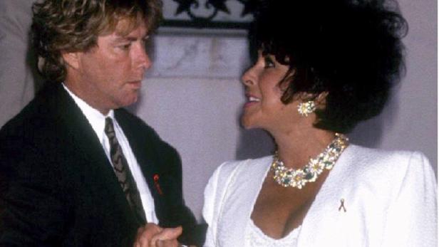 Elizabeth Taylor mit einem Mann in einem Anzug, beide tragen eine rote Schleife.