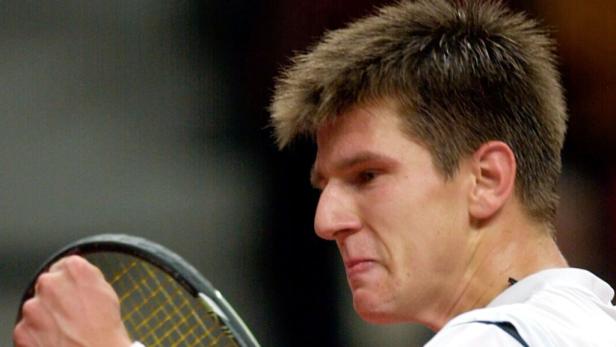 Ein Tennisspieler mit angespanntem Gesichtsausdruck hält einen Tennisschläger.