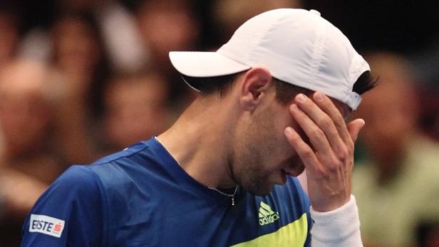 Ein Tennisspieler mit weißer Kappe hält sich enttäuscht die Hand vor das Gesicht.