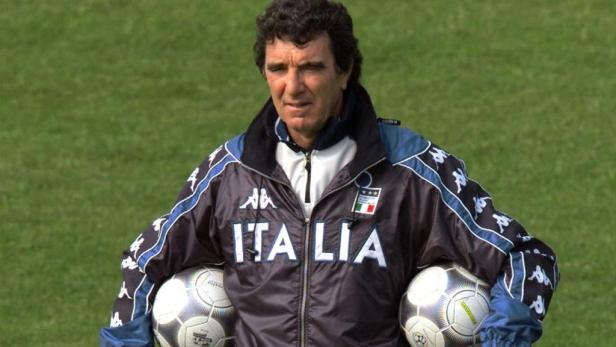 Ein Mann in einer „Italia“-Jacke hält zwei Fußbälle.