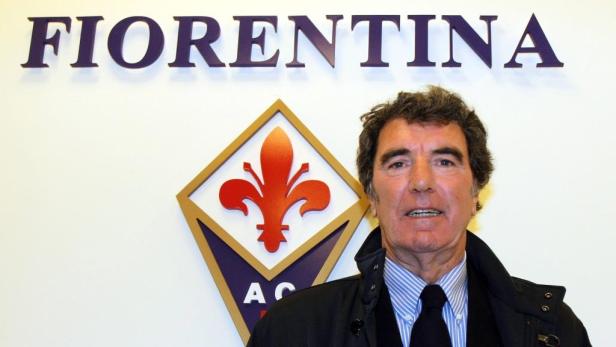 Ein Mann steht vor dem Logo des AC Florenz.