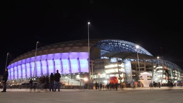 Das Stadion in Posen ist nachts beleuchtet und von Menschen umgeben.